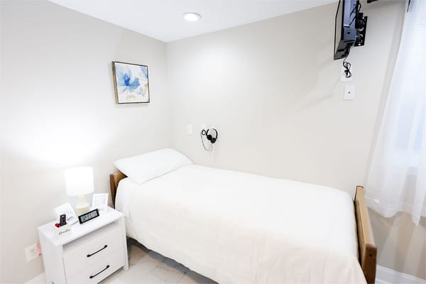 Simple, cozy resident bedroom with a bed and bedside table