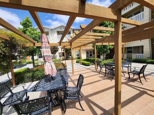 Outdoor patio with tables and chairs at Tyrol Plaza Senior Apartments