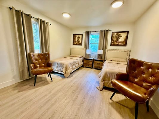 Bright shared resident room with two beds and chairs