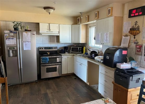 Bright kitchen with stainless steel appliances and wood flooring.