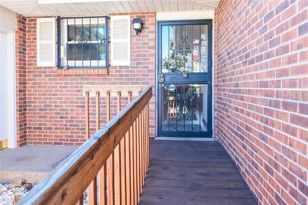 Wooden ramp leading to the front door with brick wall background