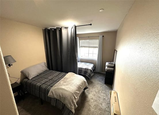 A spacious bedroom featuring two beds and a window with natural light.