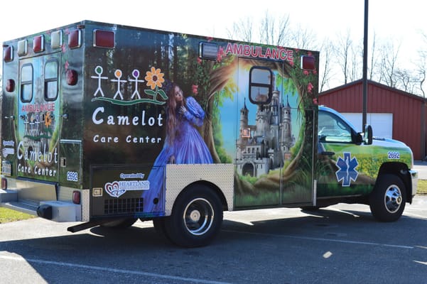 Ambulance decorated with a castle and flower design, parked outside.