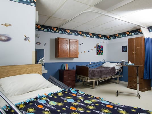 A bedroom in Camelot Care Center featuring space-themed decor and two beds.