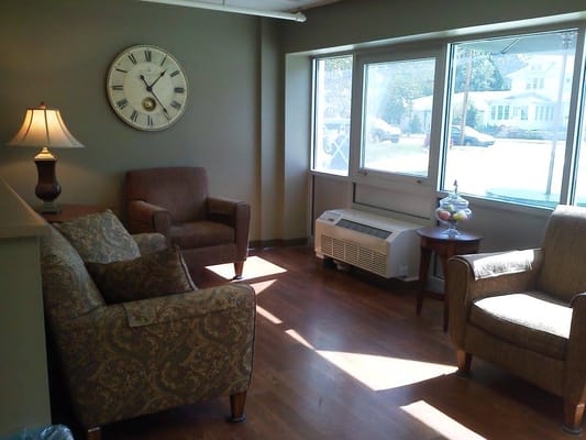 Lounge area with two armchairs and a sofa, illuminated by natural light.
