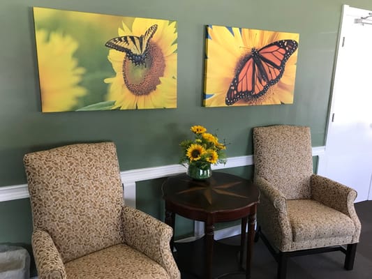 Two butterfly artworks and a flower arrangement on a table in a lobby