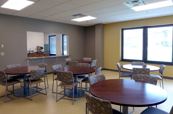 A dining area with tables and chairs, bright windows