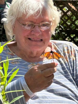 Resident holding a butterfly in a garden