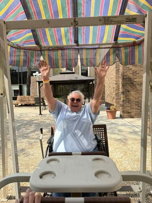 Resident enjoying time outdoors with arms raised