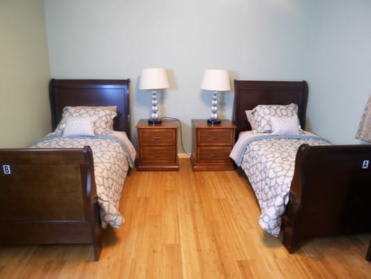 A shared resident room with two beds and lamps