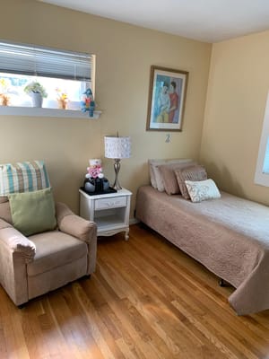 A cozy bedroom with a single bed, an armchair, and decorative items.
