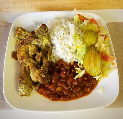 A plate of rice, seasoned meat, beans, salad, and pickles.