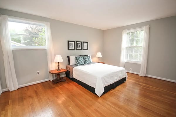 Neat bedroom with a bed, lamps, and windows