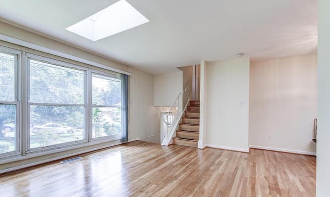 Bright living room with large windows and stairs visible