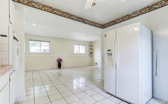 Bright kitchen with white cabinetry and large refrigerator