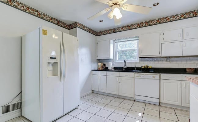Spacious kitchen with white cabinetry and modern appliances