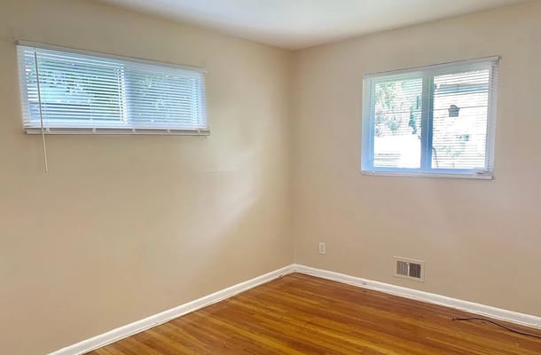 Empty room with two windows and wooden flooring