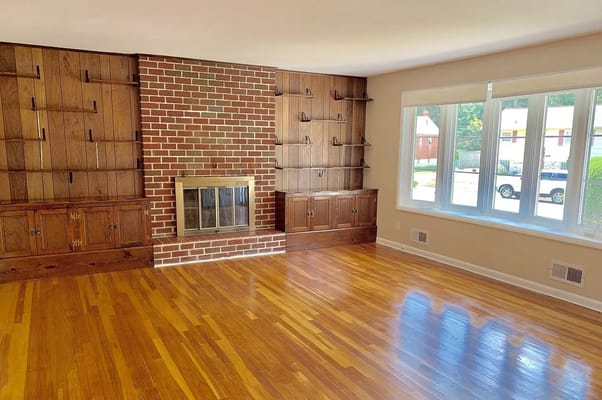 Bright living room featuring hardwood floors and a brick fireplace