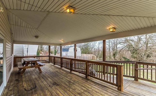 Covered porch with wooden flooring and picnic table