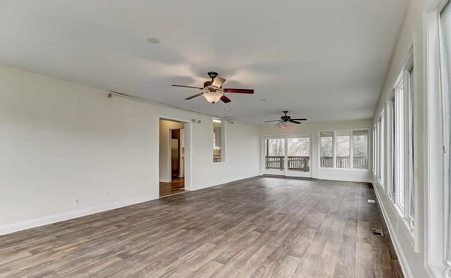 Empty living room with wood flooring and ceiling fans
