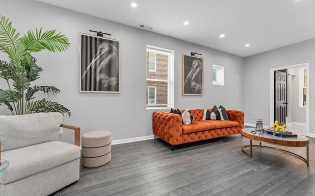 Bright and inviting living room with an orange couch and artwork.