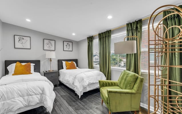 A bright, cozy bedroom with two twin beds and green curtains.