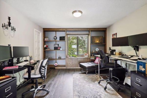 A bright office space with dual computer desks and bookshelves
