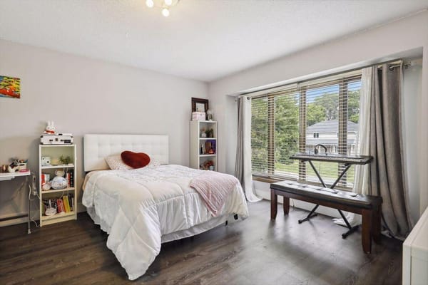 A comfortable bedroom featuring a bed, a small table, and large windows with a view.