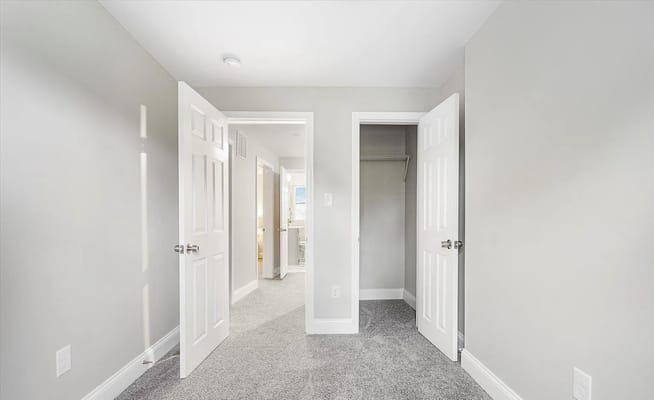 Bright, spacious room with open doors and gray carpet