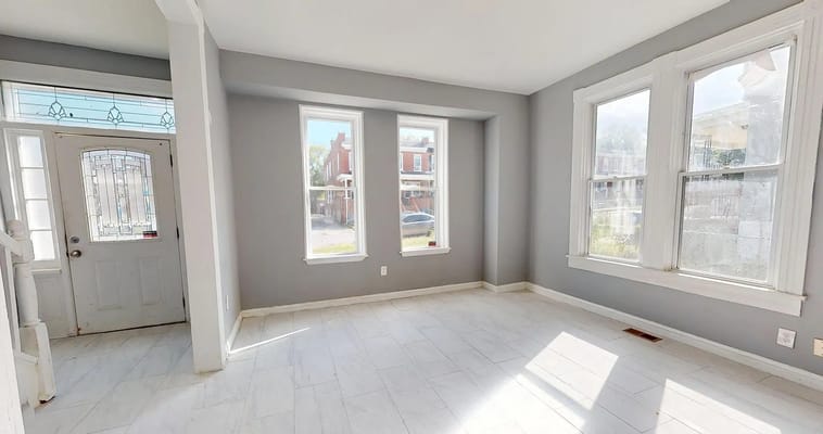 Bright, spacious living room with windows and tiled floor.