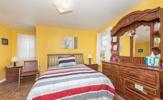 Neatly arranged bedroom with a yellow wall and wood furniture