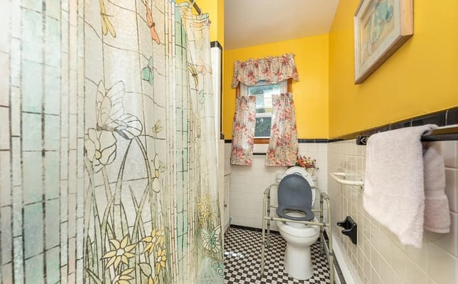 Accessible bathroom with floral shower curtain and yellow walls