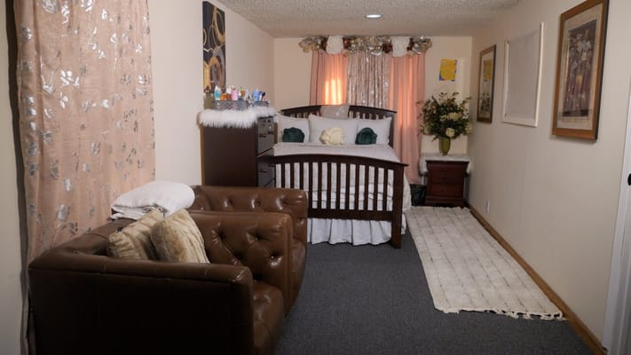 A well-decorated bedroom with a bed and seating area at T&F Assisted Living.