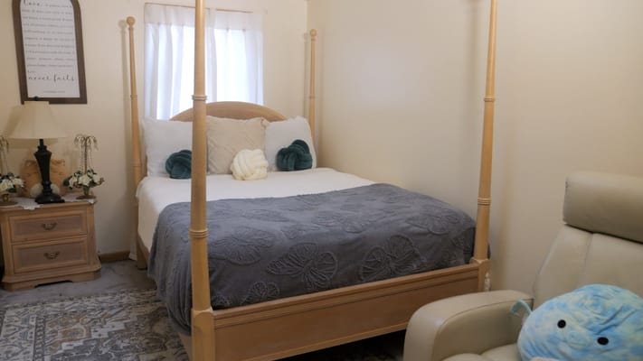 A well-furnished bedroom with a bed, pillows, and decorative items.