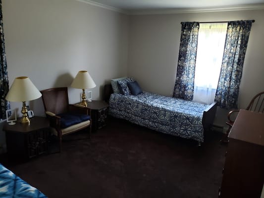 A cozy bedroom with two beds, lamps, and floral curtains.