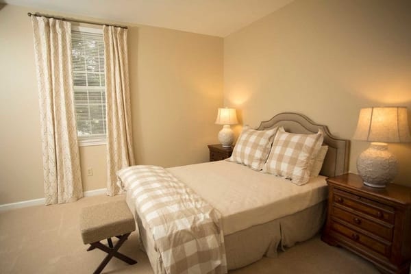 A well-lit bedroom with a bed, side tables, and curtains
