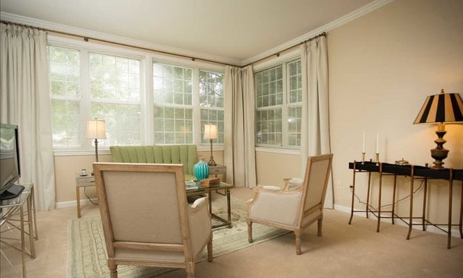 A cozy living room with green sofa and large windows.