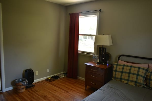 A cozy bedroom with a bed, nightstand, and window