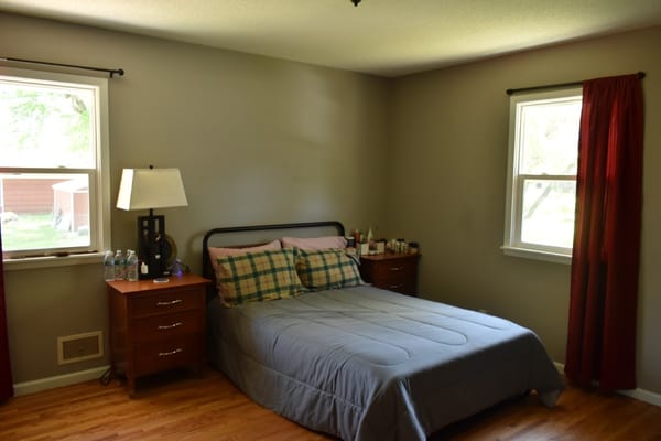 A neatly arranged bedroom with a bed, bedside tables, and a lamp.
