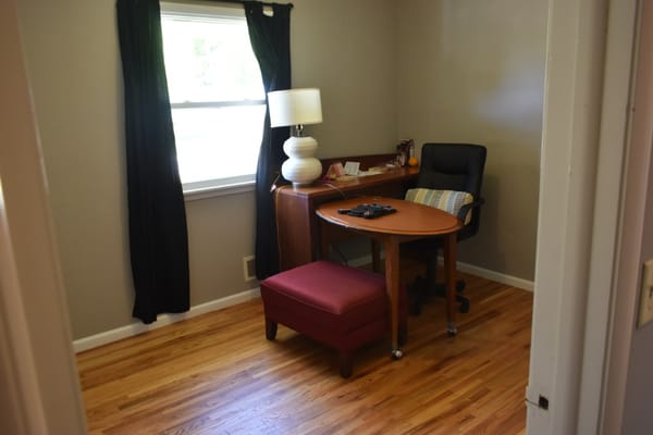 A private room featuring a desk, chair, and lamp.