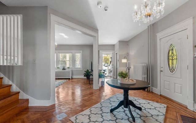 Welcoming lobby area with a chandelier and wooden staircase