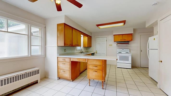 Interior view of a kitchen with wooden cabinets and white appliances.