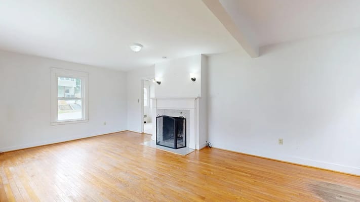 Spacious living room with hardwood floors and a fireplace.