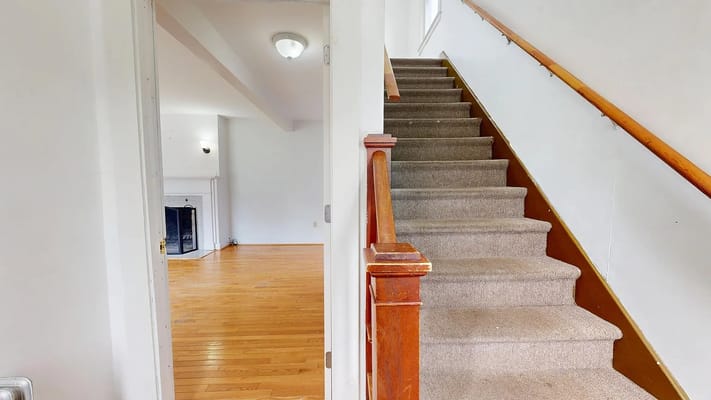 View of a staircase leading to a living area with wooden floors.