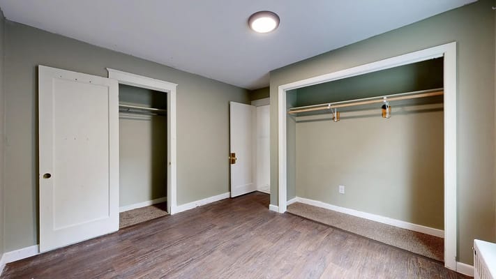 Empty closet space with wooden floor and green walls.