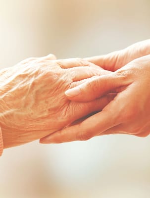 Close-up of a caregiver holding a senior's hand