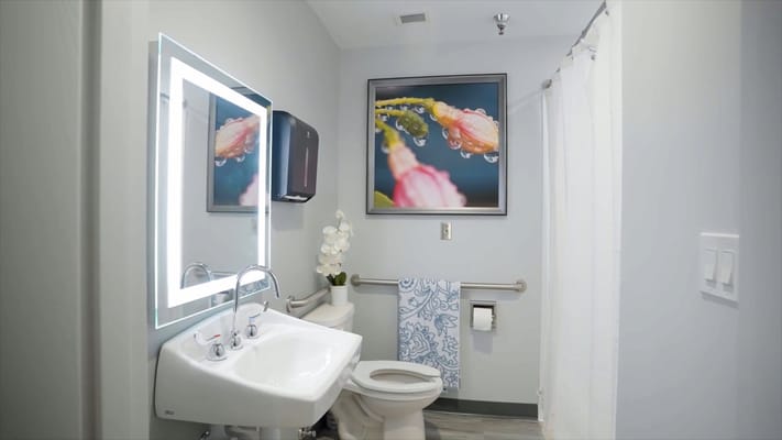 Bright and clean bathroom with a sink, toilet, and decorative artwork
