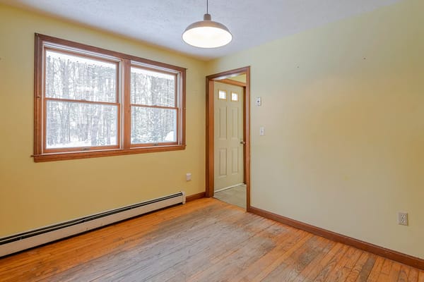 Interior view of a room with windows and a door, featuring wooden floors.