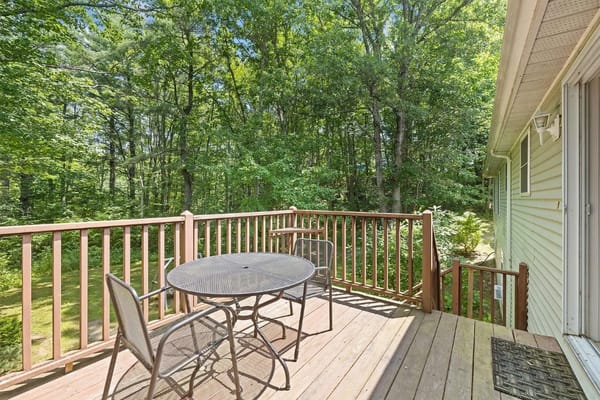 A deck with a table and chairs overlooking a wooded area.
