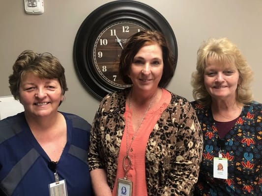 Three staff members posing together in a common area